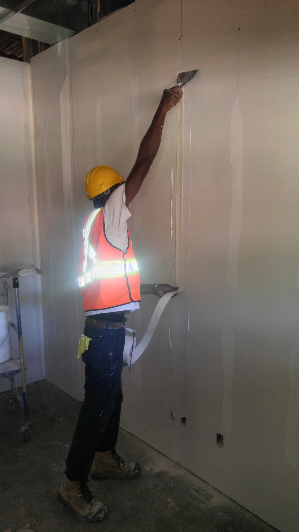 Drywaller taping a vertical drywall seam